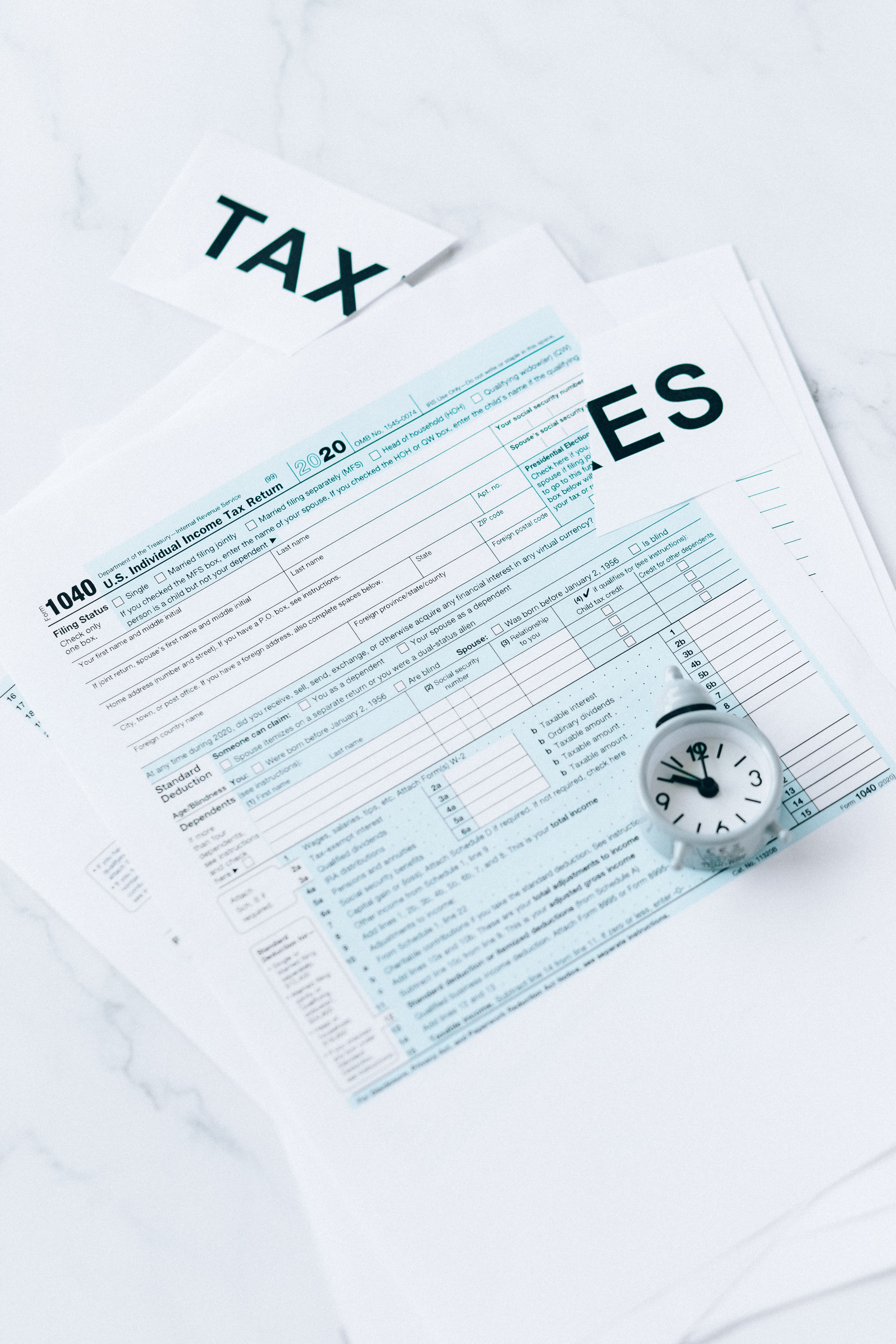 Tax forms and clock on a clean marble desk